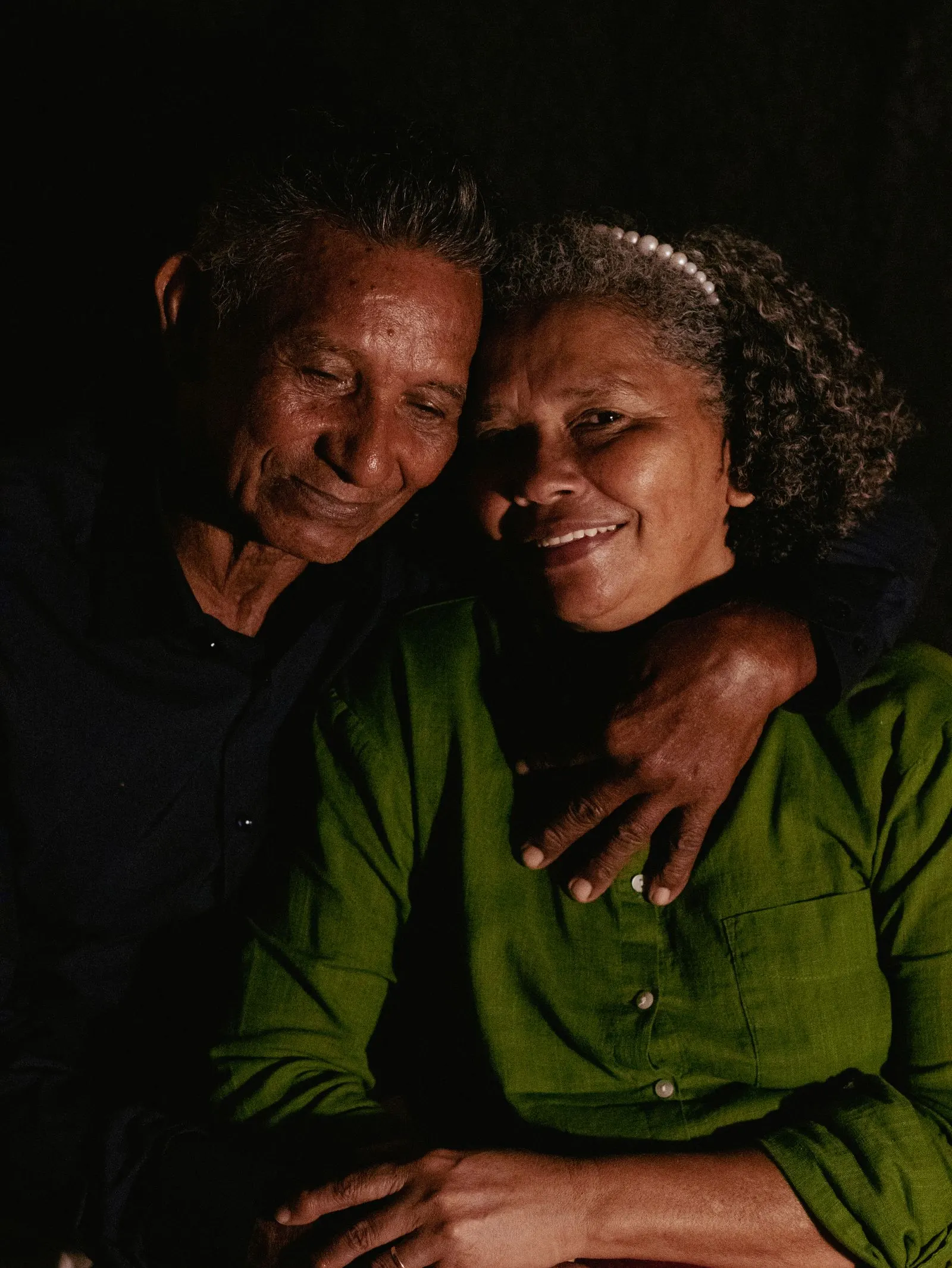 An older Black couple smiling in a warm embrace
