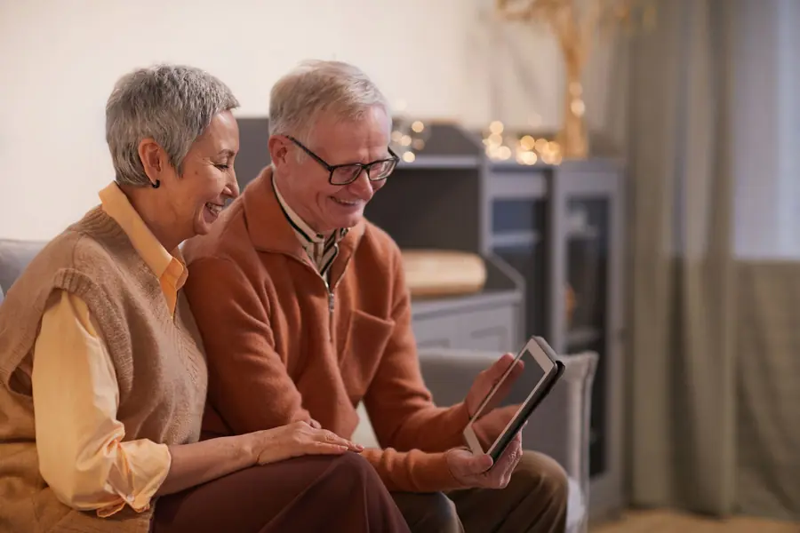 An older couple on the couch checking their plans on a tablet