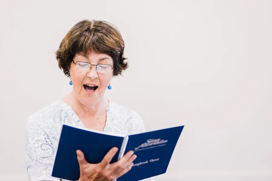 Older woman singing joyfully from a hymnal