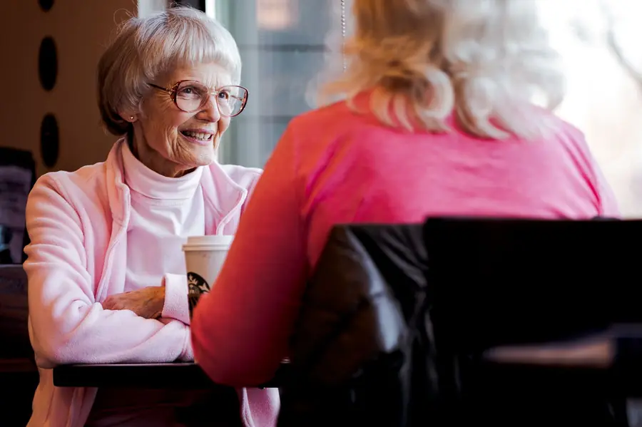 Older woman laughing over coffee with a friend at a cafe